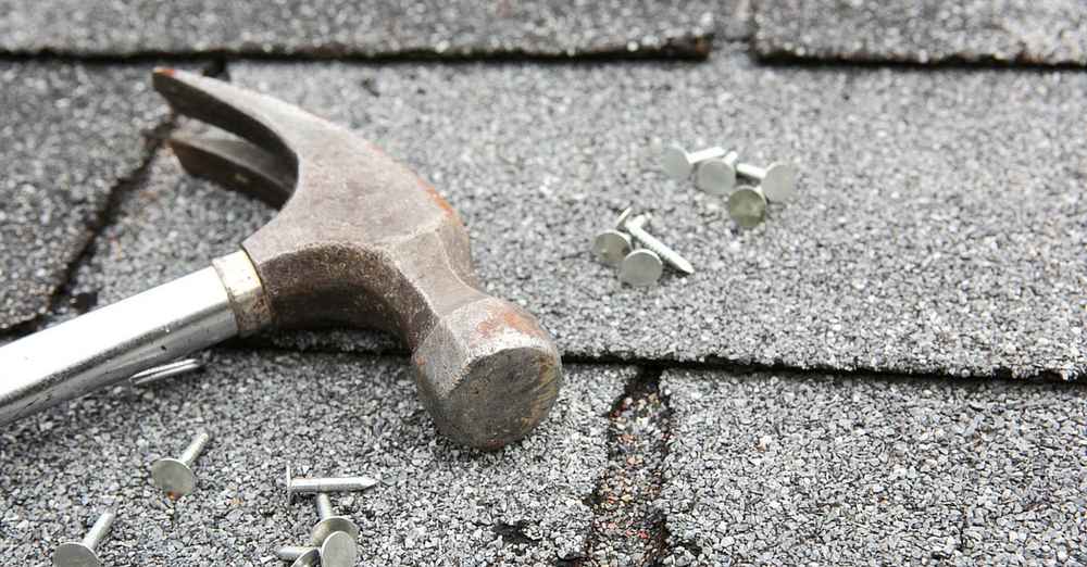 Hammer with nails on an old asphalt shingle roof